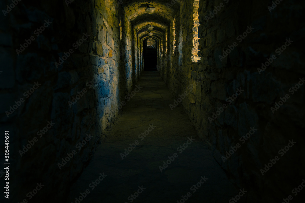 medieval castle empty corridor twilight cold and scary environment passage without people lighting from loop holes