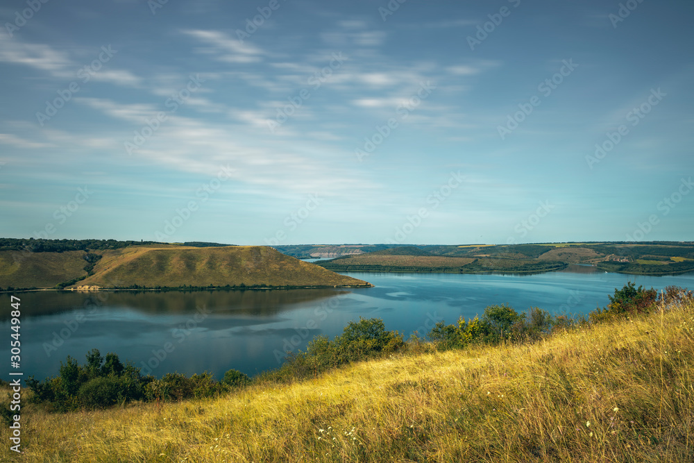 nature reserve landscape background photography of hill land and lake summer time scenic view with fuzzy cloudy sky 