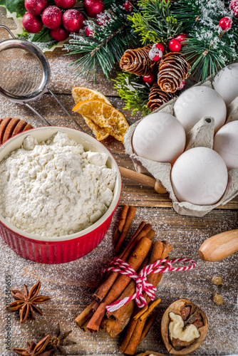 Christmas baking background. Ingredients for cooking xmas baking. Flour, eggs, sugar, berry, spices on wooden background with christmas decor,. Top view copy space.