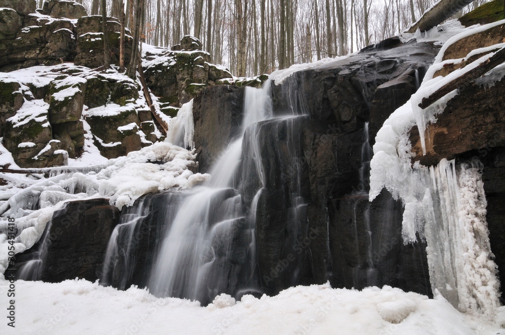 A small mountain waterfall covered in snow
