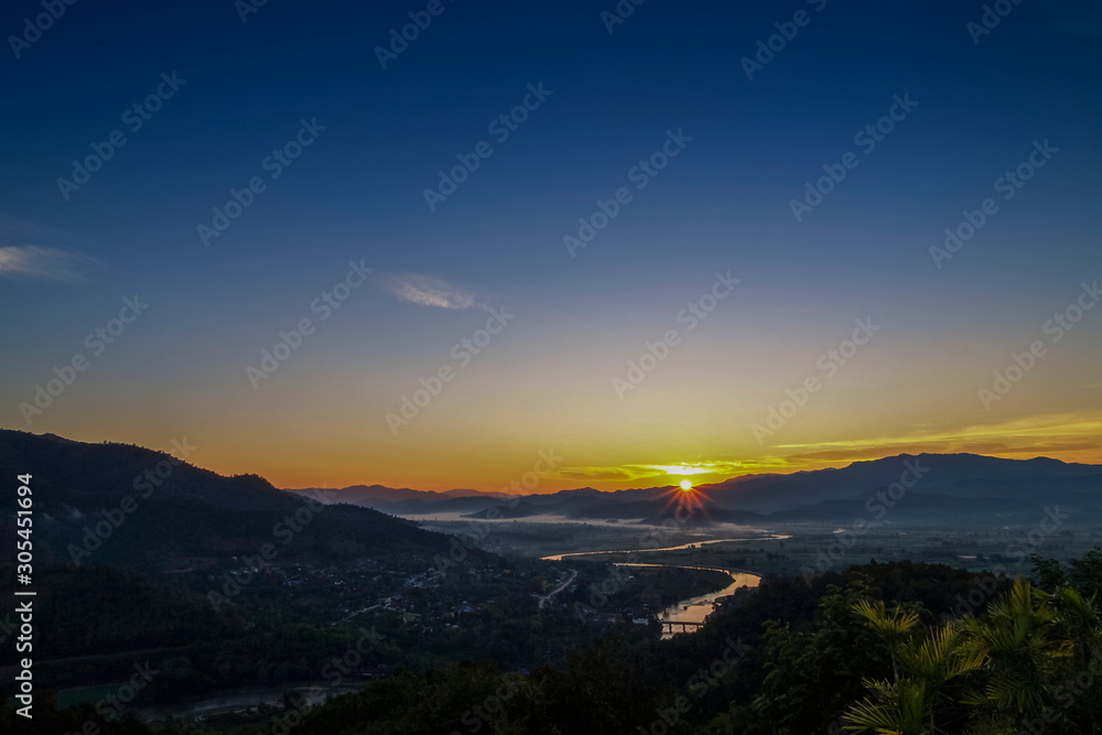 Mountain view misty morning above Kok river and Tha Ton City around with soft mist in valley and blue sky background, sunrise at Wat Tha Ton, Tha Ton District, Fang, Chiang Mai, northern of Thailand.