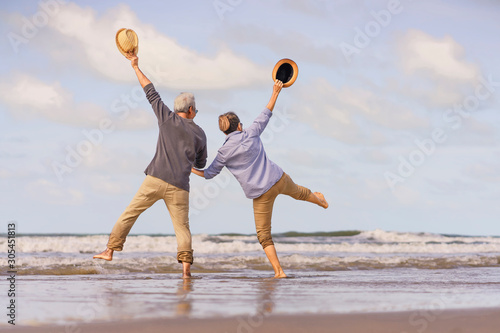 Asian senior couple jumping on the beach.elderly honeymoon together very happiness after retirement.plan life insurance.Activity after retirement on summertime
