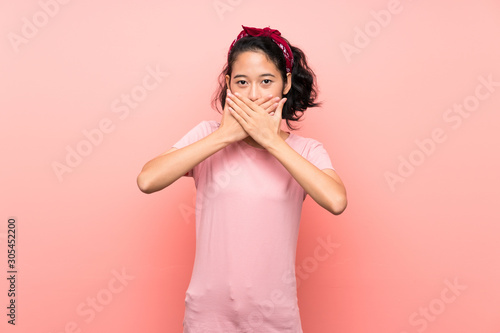 Asian young woman over isolated pink background covering mouth with hands