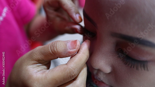 Make-up artist work on her client, beautiful teen girl, Pekalongan Indonesia