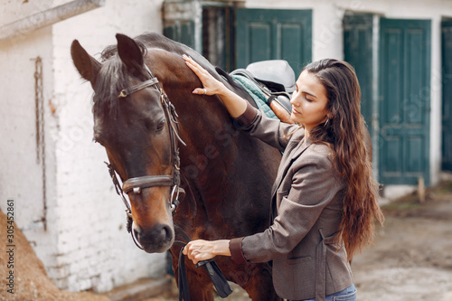 Woman standing with a horse. Lady in a brown jacket