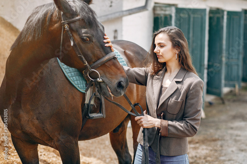 Woman standing with a horse. Lady in a brown jacket © prostooleh