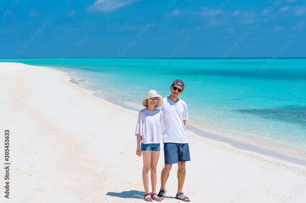 Dad and daughter enjoy vacation. Asian man and teenager daughter standing side by side on white sand beach and clear blue sea looking, smiling to camera. Concept of friendship and summer vacation time