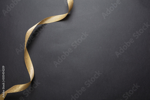 Golden ribbon curl on black color background. Minimal card template photo