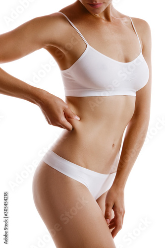Young body of girl in white underwear, showing fat on her side, posing isolated on white. Plastic surgery, aesthetic cosmetology concept. Close-up.