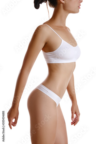 Perfect, slim, toned, young body of a girl in white underwear posing isolated on white. Plastic surgery and aesthetic cosmetology concept. Close-up.