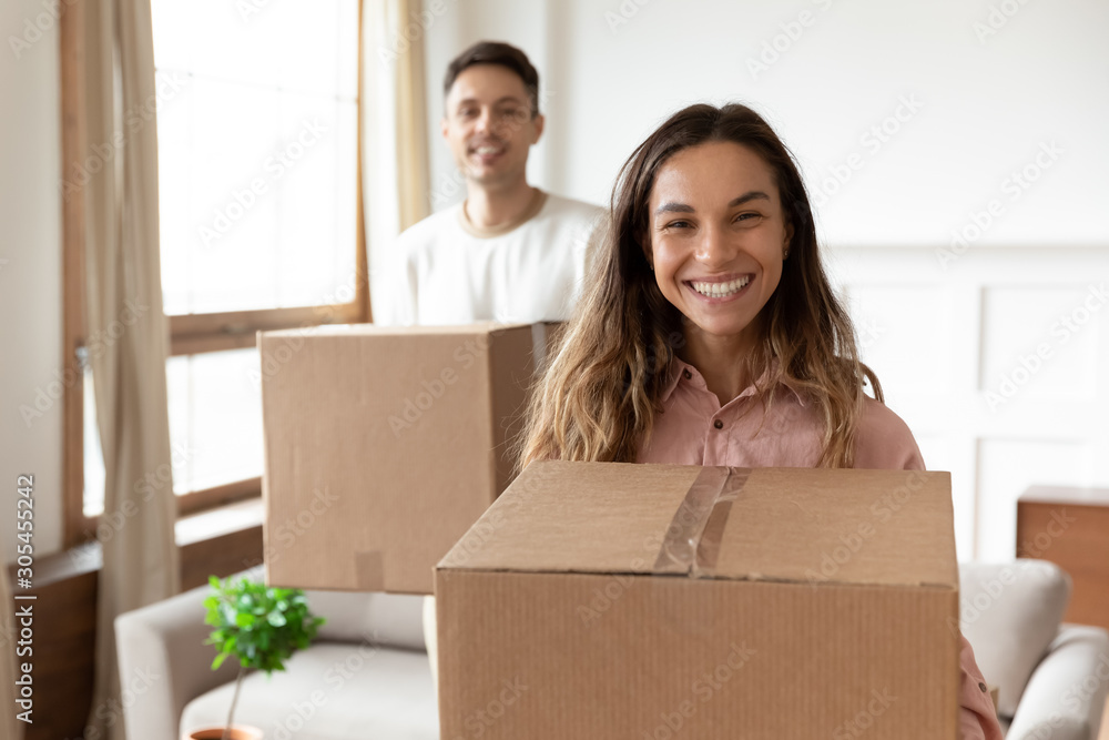 Smiling wife holding box relocating into new home with husband Smiling wife holding box relocating into new home with husband