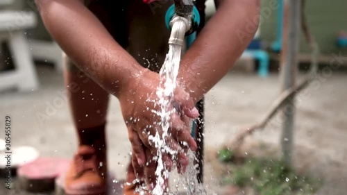 Washing hands in water draining from rustic tap.