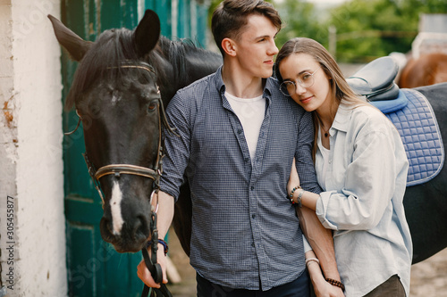 Couple on a ranch. Pair standing with a horse. Girl with her boyfriend