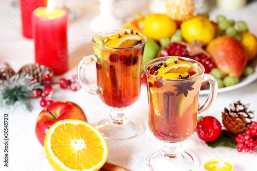 hot winter drink Cranberry Apple Cider Punch. Garnish with apples, oranges, and cranberries. hot apple cider with spices on a festive table on Christmas or New Year.