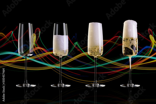 Four glasses of champagne on a black background with an abstract pattern. The empty glass, half glass, full glass, a glass with a large foam.