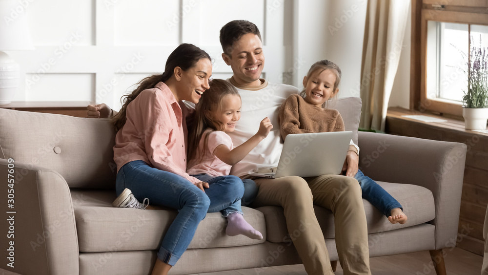 Cheerful parents and kids using laptop having fun at home