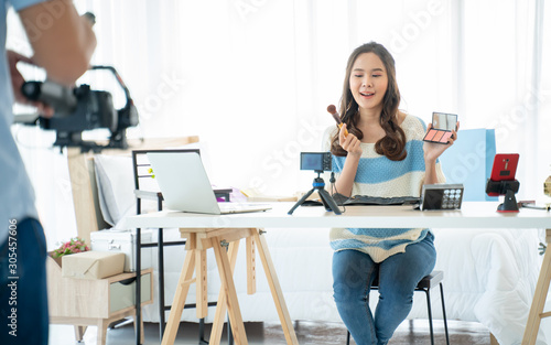 Business online on Social network sharing and online community concept.Young woman working as blogger,recording video tutorial,vlog and sale product online shopping in front of camera for Internet.