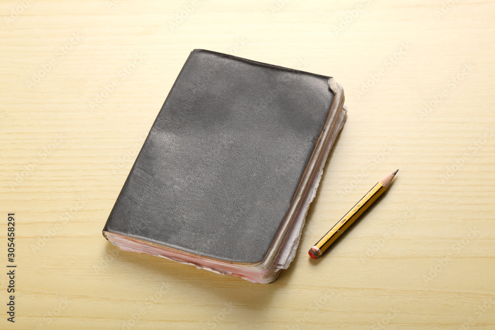old agenda and a pencil rest on a wooden table with copy space for your text old agenda and a pencil rest on a wooden table with copy space for your text