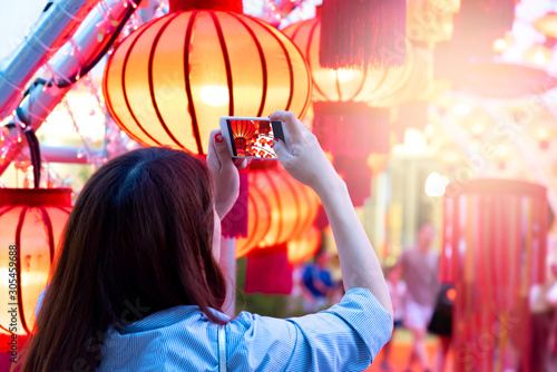 Back of Young asian woman using smart phone outdoor taking photos of red lanterns Chinese style during Chinese new year festival chinatown.