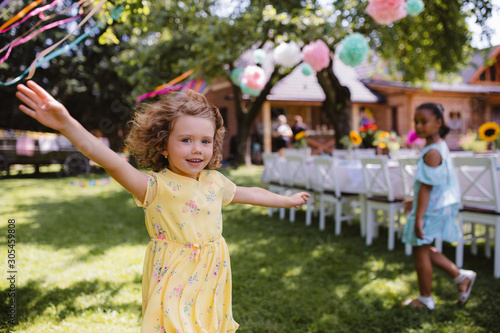 Small girl running outdoors in garden in summer, birthday celebration concept.
