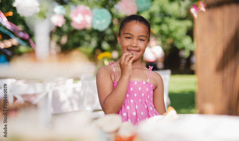 Small girl standing outdoors in garden in summer, birthday celebration concept. Small girl standing outdoors in garden in summer, birthday celebration concept.