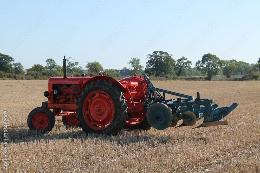 Fototapeta premium A Vintage Tractor and Plough in a Farming Field.