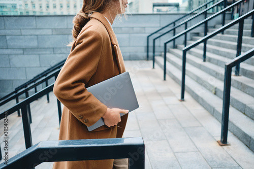 Fotografija Close up young businesswoman in coat with laptop on street