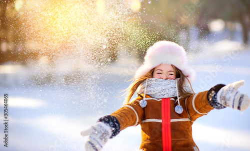 A girl walks in the winter forest, throws snow and has fun. Outdoor activities.