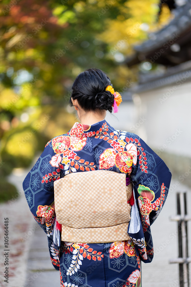 Geishas girl wearing Japanese kimono among red wooden Tori Gate at Fushimi  Inari Shrine in Kyoto,