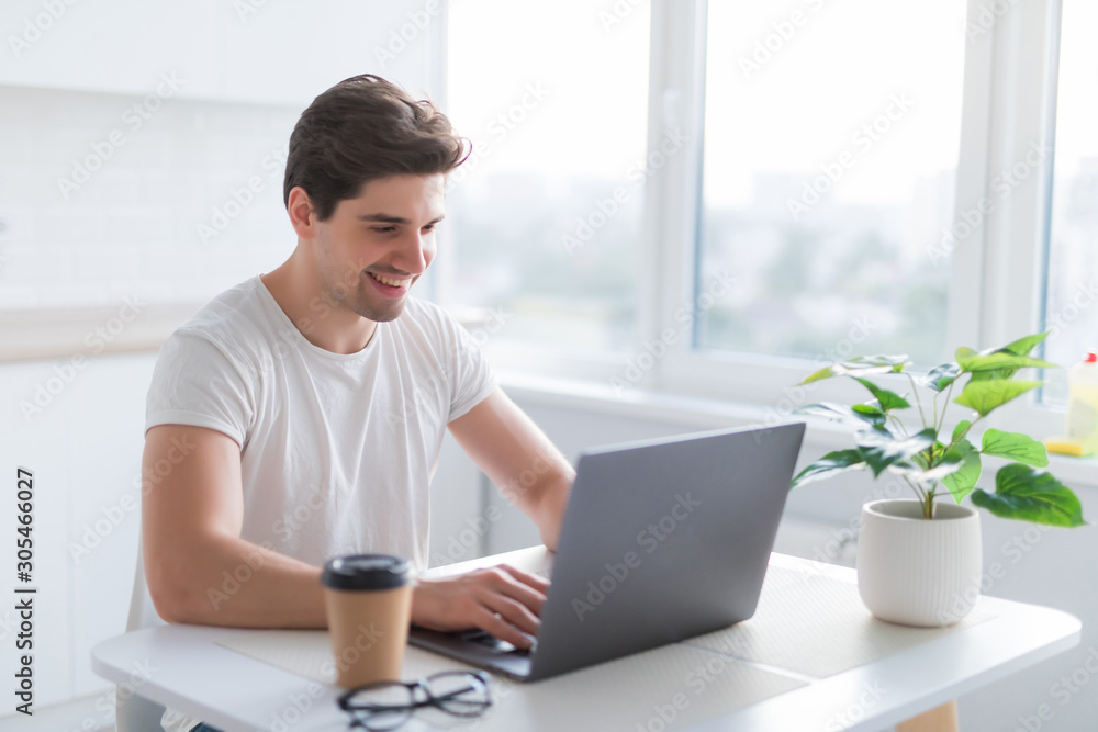 Portrait of a smiling man using laptop in the kitchen at home Portrait of a smiling man using laptop in the kitchen at home