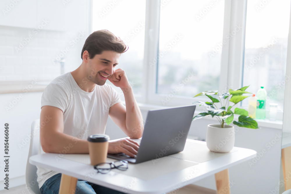 Portrait of handsome man sitting at table at home with laptop computer, smiling at camera. Portrait of handsome man sitting at table at home with laptop computer, smiling at camera.