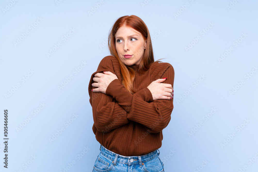 Young redhead woman over isolated blue background freezing Young redhead woman over isolated blue background freezing