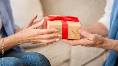 Presenting Christmas gift. Senior couple exchanging xmas presents