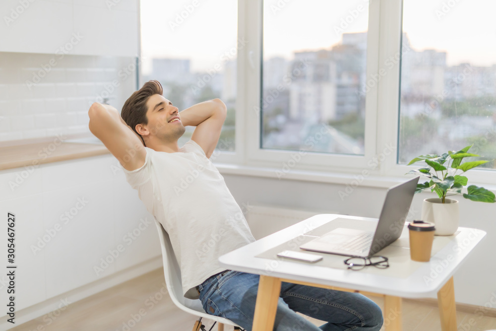 Smiling young businessman with laptop leaning back in his home office Smiling young businessman with laptop leaning back in his home office