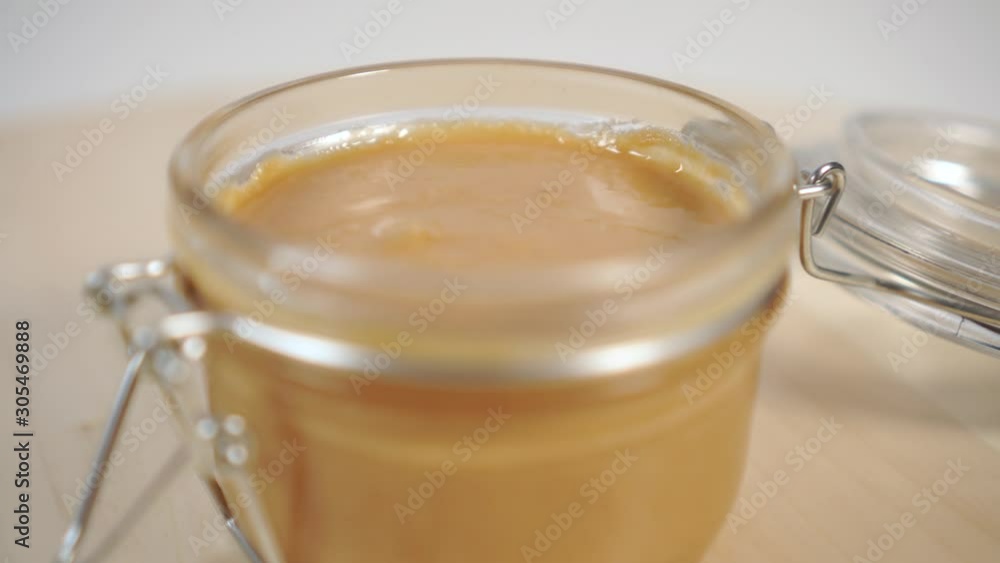 Closeup peanut butter in a glass jar with a metal fastener on a wooden table. Rotation. Healthy Organic Breakfast Closeup peanut butter in a glass jar with a metal fastener on a wooden table. Rotation. Healthy Organic Breakfast