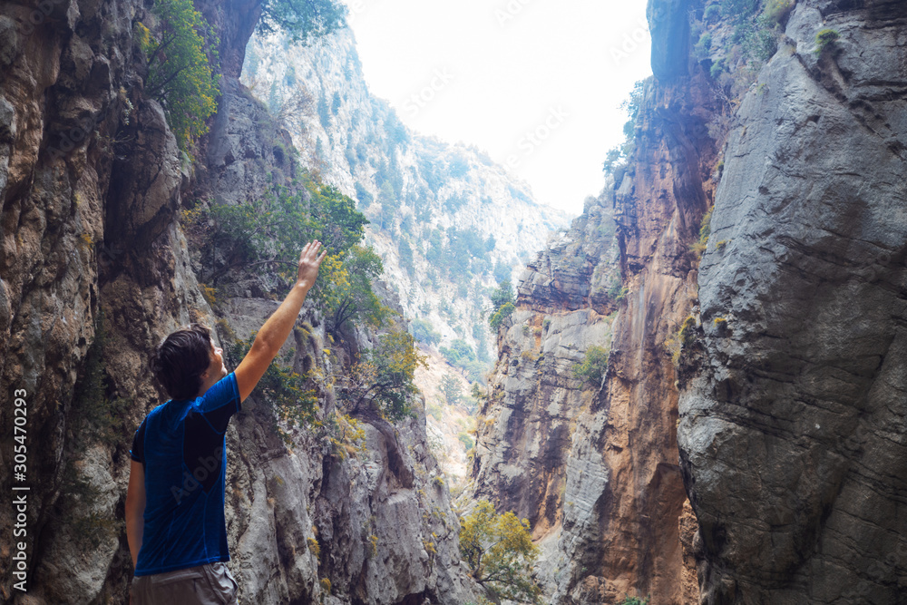 Obraz premium young man climbed a rock, trekking in a gorge. Unity with nature