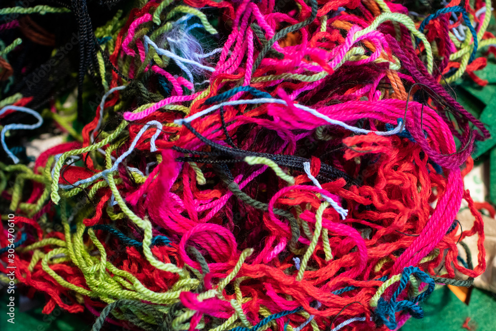 Wool threads with many colors woven together to form a texture of lines. abstract background composed of woven wool and cotton threads, a messy pink ball of yarn. Chaotic , complicated representation