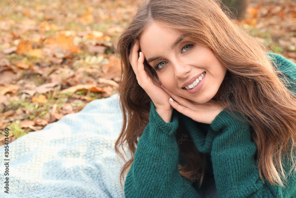 Portrait of stylish young woman lying on plaid in autumn park Portrait of stylish young woman lying on plaid in autumn park