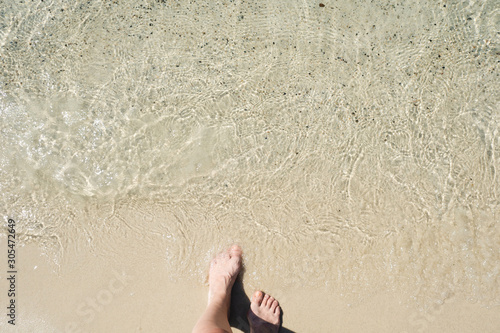 Step into the sea, women's feet on the sand before the surf