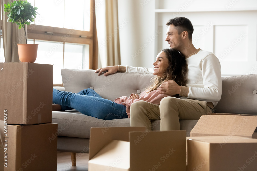 Happy couple dreaming relaxing in own home with boxes Happy couple dreaming relaxing in own home with boxes
