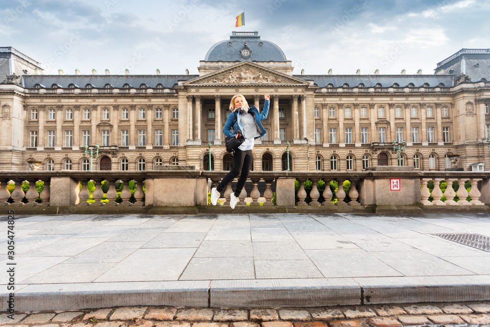 Fototapeta premium Woman jumps up on the background of the Royal Palace in Brussels, Belgium