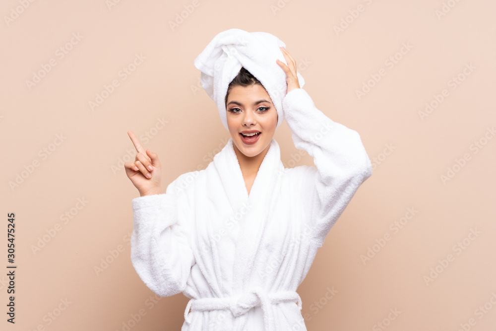 Teenager girl in a bathrobe over isolated background surprised and pointing finger to the side Teenager girl in a bathrobe over isolated background surprised and pointing finger to the side