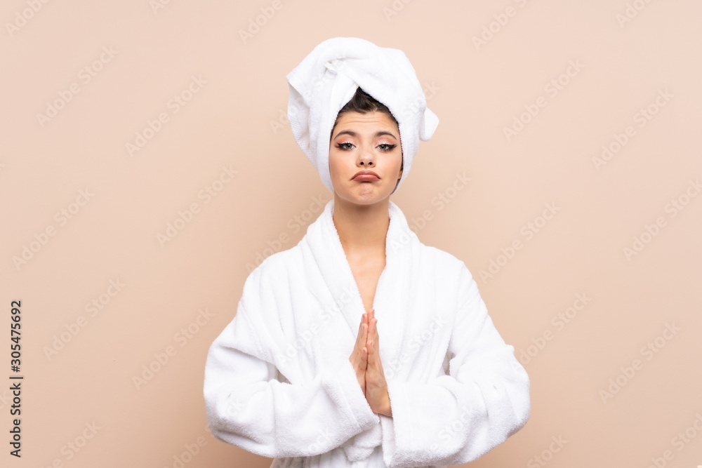 Teenager girl in a bathrobe over isolated background pleading Teenager girl in a bathrobe over isolated background pleading