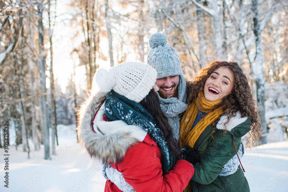 A group of cheerful young friends having fun outdoors in snow in winter forest. A group of cheerful young friends having fun outdoors in snow in winter forest.