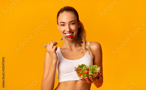 Fotografia Positive Fitness Lady Enjoying Veggie Salad, Studio Shot