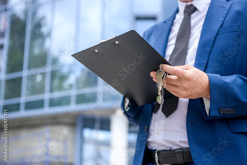 Businessman with clipboard standing against new building