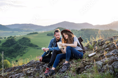 Young tourist couple travellers sitting in nature, resting after hiking. © Halfpoint