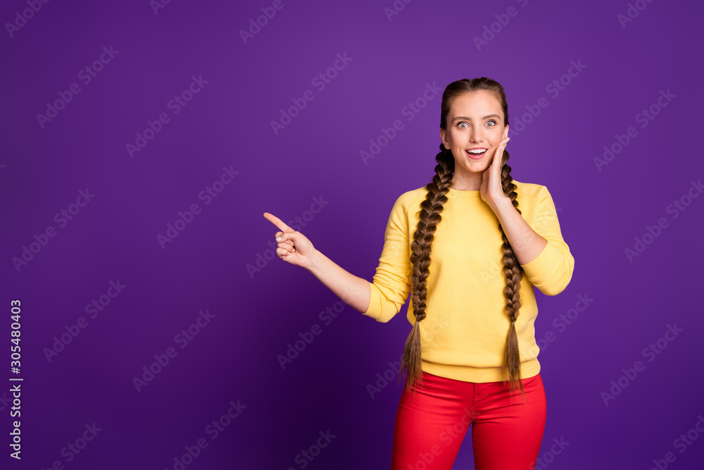 Fototapeta premium Photo of pretty lady long braids indicating finger empty space advising cool low shopping prices wear casual yellow pullover red trousers isolated purple color background