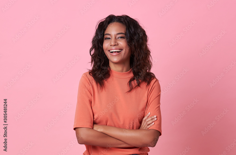Happy smiling beautiful african woman looking at camera wearing casual orange t-shirt isolated on pink background. Happy smiling beautiful african woman looking at camera wearing casual orange t-shirt isolated on pink background.