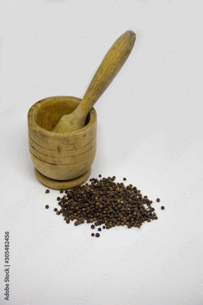 black pepper in a wooden mortar on a white background black pepper in a wooden mortar on a white background
